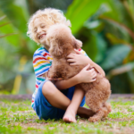 a kid isitting n the yard hugging the dog